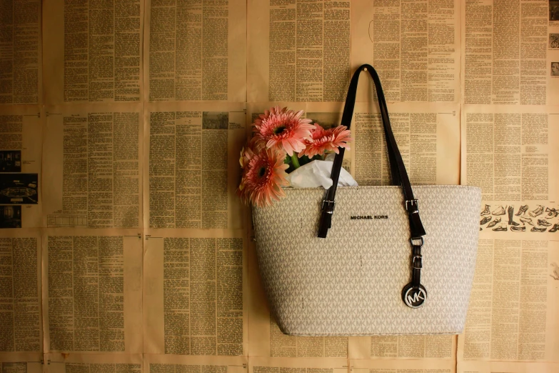 a purse sitting on top of a newspaper covered wall, by Carey Morris, pexels contest winner, beige, key art, flowers, ariana grande photography