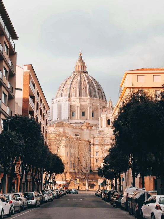 a street lined with parked cars next to tall buildings, by Cagnaccio di San Pietro, pexels contest winner, neoclassicism, dome, profile image, vatican map room, golden hour closeup photo