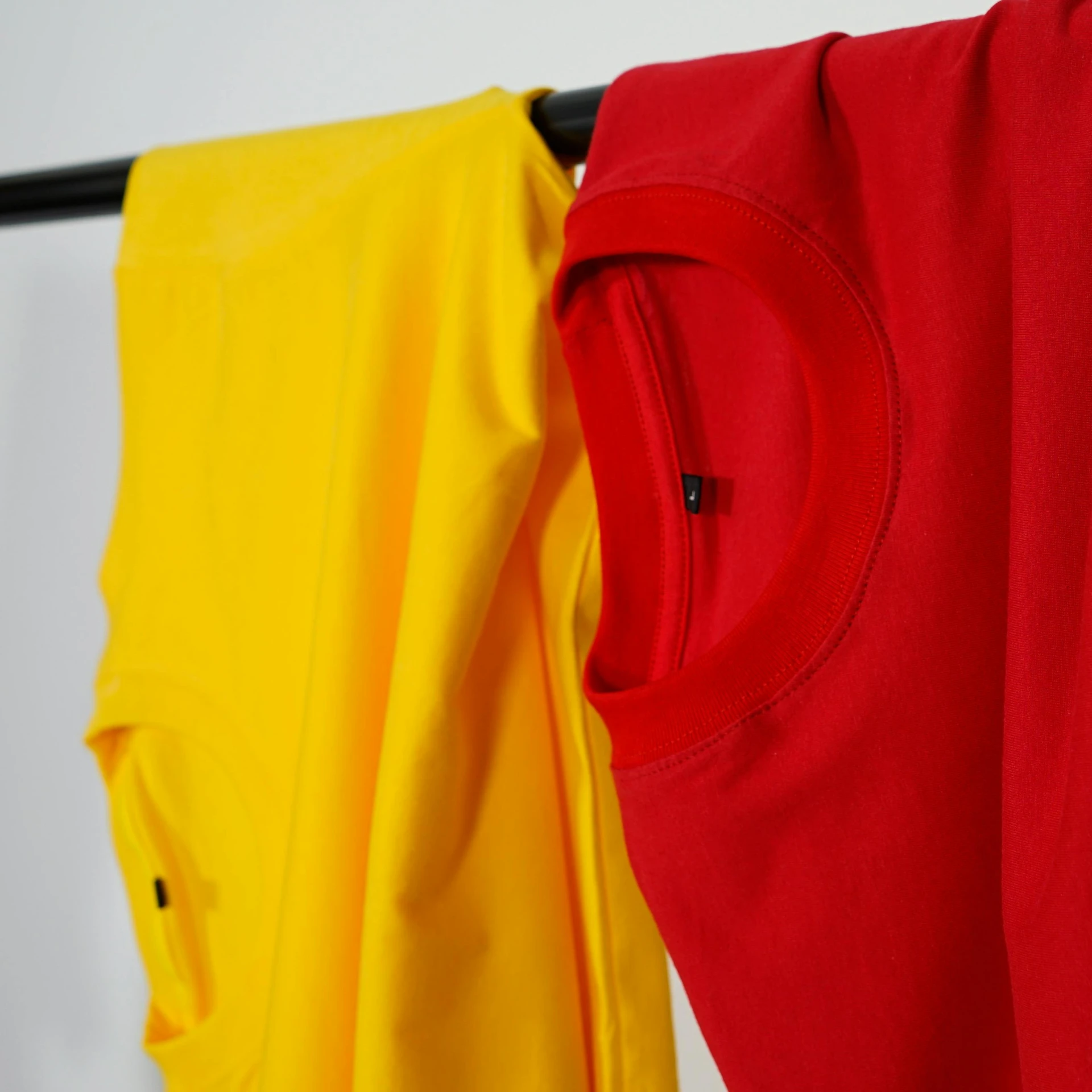 a pair of yellow and red shirts hanging on a clothes line, inspired by Tommaso Redi, pexels, minimalism, upper body close - up, solid colours material, product introduction photo