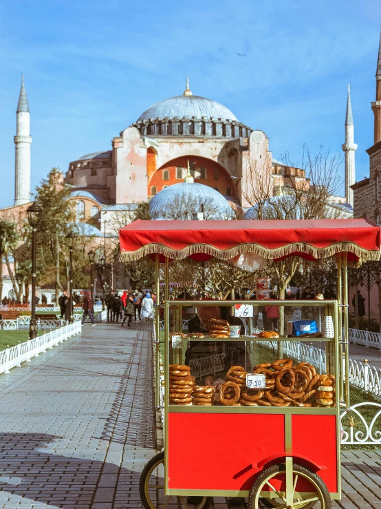 a cart that is sitting in front of a building, a colorized photo, by Julia Pishtar, hurufiyya, with great domes and arches, in the shape of a cinnamon roll, turkey, 🚿🗝📝