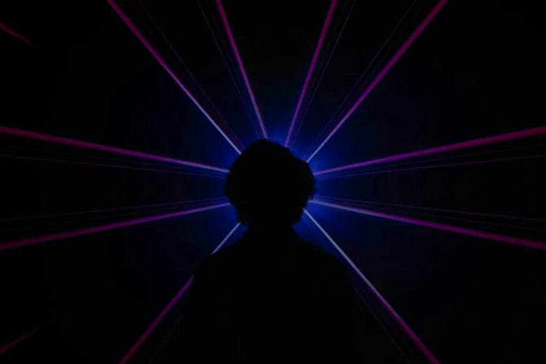 a person standing in front of a blue light, inspired by John Carpenter, unsplash, light and space, crown of (pink lasers), silhouetted, light over boy, glowing violet laser beam eyes