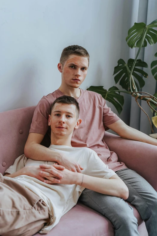 a couple of men sitting on top of a pink couch, a picture, by Cosmo Alexander, unsplash, renaissance, vitalik buterin, holding each other, teenage boy, lovingly looking at camera