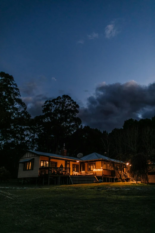 a house sitting on top of a lush green field, night time australian outback, dimly-lit cozy tavern, cottagecore, brown