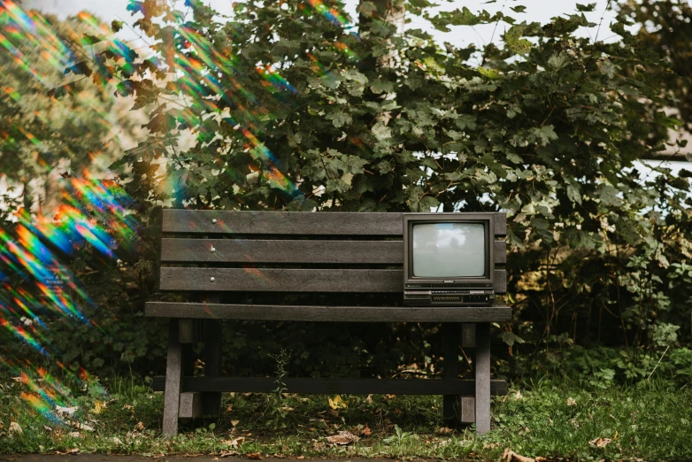 a television sitting on top of a wooden bench, inspired by Elsa Bleda, unsplash, video art, sitting in the garden, 1 9 8 0 s tech, analogue photo, old computer