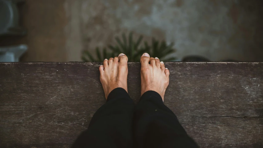 a person sitting on top of a wooden bench, by Victorine Foot, pexels contest winner, exposed toes, background image, manly, tall thin