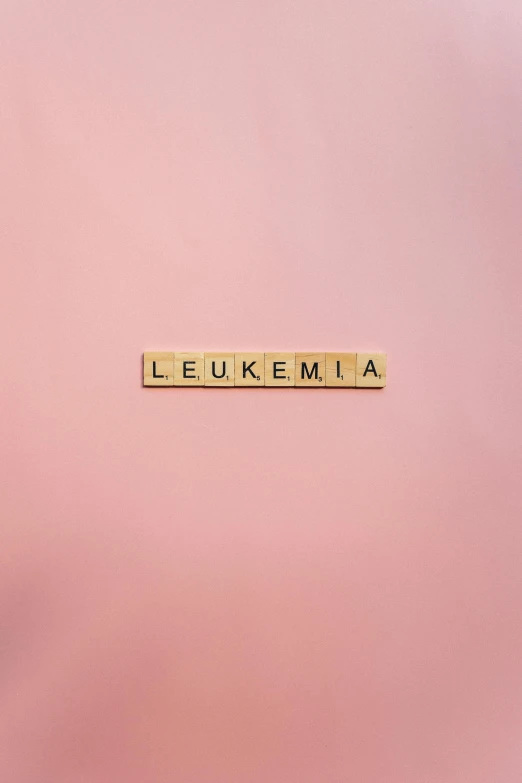 a close up of a wooden block with the word leukemia written on it, an album cover, inspired by Louise Abbéma, trending on unsplash, letterism, brightly lit pink room, on a gray background, taken with sony alpha 9, from the duchy of lituania