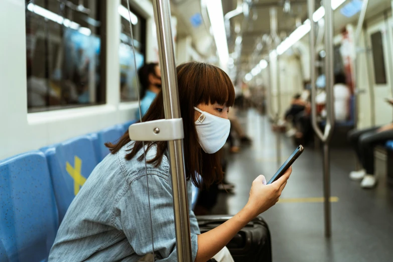 a woman wearing a face mask on a subway, trending on pexels, happening, square, phone, molecular, iu