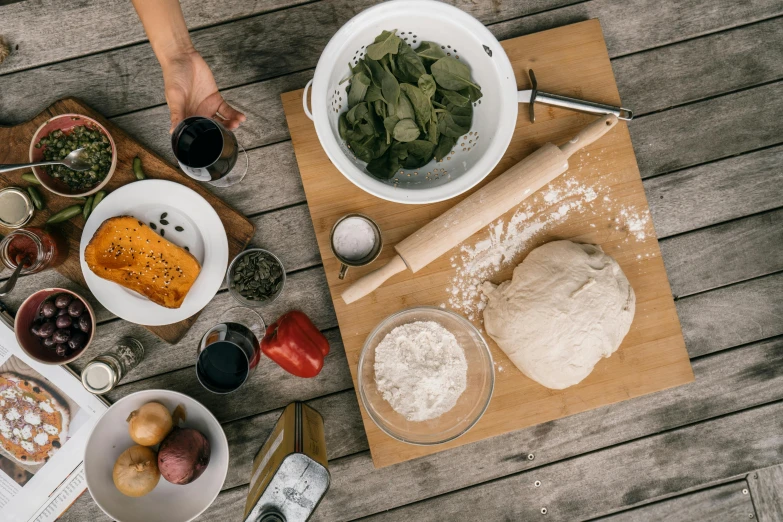 a wooden table topped with bowls of food, inspired by Géza Dósa, pexels contest winner, process art, cooking pizza, holding a baguette, high resolution product photo, back - shot