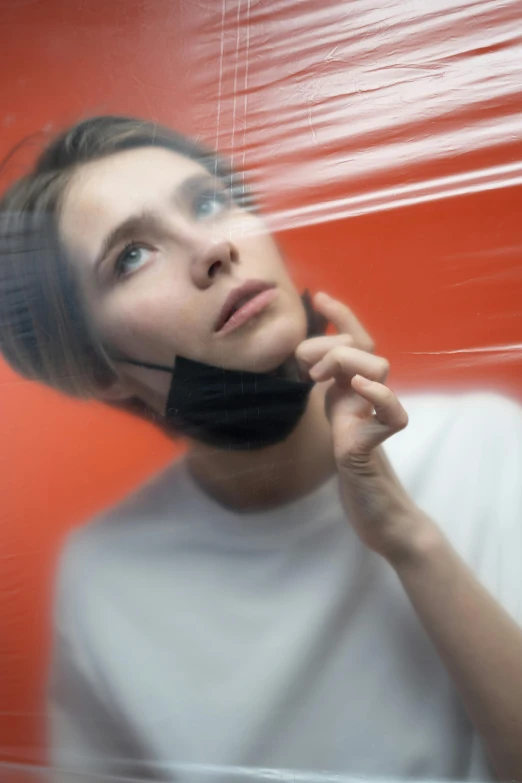 a close up of a person talking on a cell phone, an album cover, by Adam Marczyński, trending on pexels, surrealism, portrait androgynous girl, wearing translucent veils, suspended in zero gravity, angular jawline