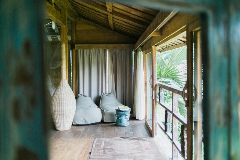 a living room filled with furniture next to a window, by Jessie Algie, unsplash, bamboo huts, beachwood treehouse, spa, sarong