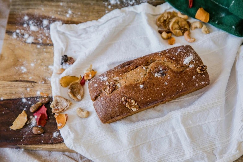 a loaf of bread sitting on top of a wooden cutting board, by Helen Stevenson, unsplash, festive, cake, caramel, linen