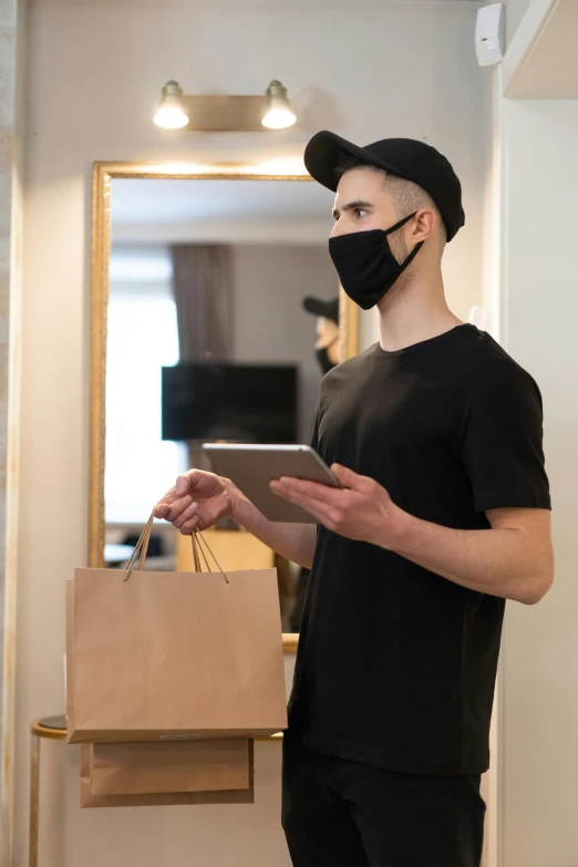 a man wearing a face mask and holding a bag, by Adam Rex, ecommerce photograph, fancy apartment, holding a clipboard, black