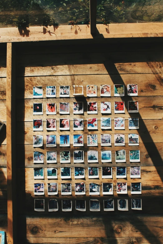 a wooden wall with a bunch of pictures on it, a polaroid photo, inspired by Elsa Bleda, unsplash, square shapes, outdoor photo, unsplash 4k, a high angle shot