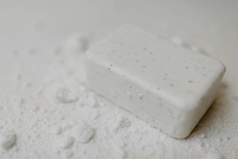 a soap bar sitting on top of a pile of white powder, trending on pexels, grayish, speckled, glazed, on high-quality paper