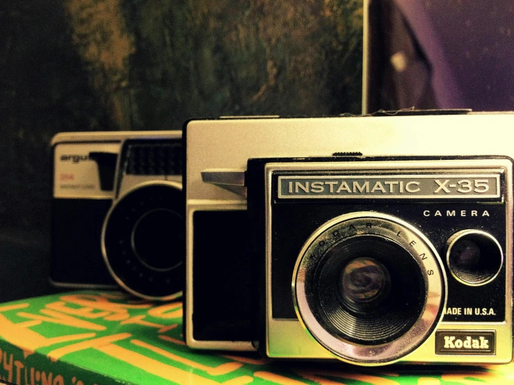 a couple of cameras sitting on top of a box, a polaroid photo, cineastic, imaginfx, instagram post, phantasmagoric