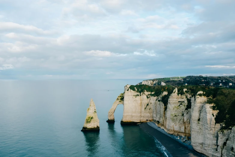 two large rocks in the middle of a body of water, by Raphaël Collin, pexels contest winner, romanticism, coastal cliffs, french architecture, slide show