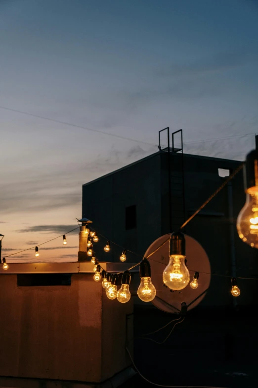 a group of light bulbs sitting on top of a roof, in the evening, roof garden, unsplash photo contest winner, party lights