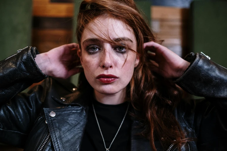 a close up of a person wearing a leather jacket, a portrait, inspired by Nan Goldin, trending on pexels, she looks like a mix of grimes, readhead, promotional image, devastated