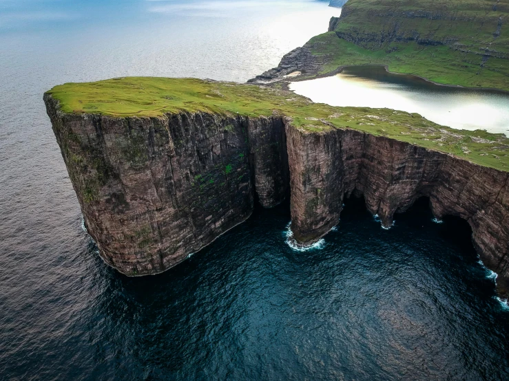 a cliff in the middle of a body of water, by Jesper Knudsen, pexels contest winner, land art, orkney islands, flying islands, national geographics, huge gargantuan scale