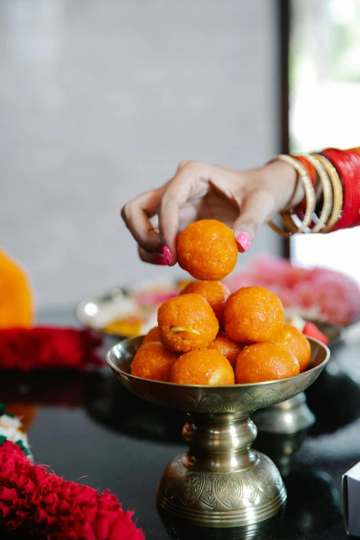 a person putting oranges in a bowl on a table, hindu ornaments, excitement, square, scintillating