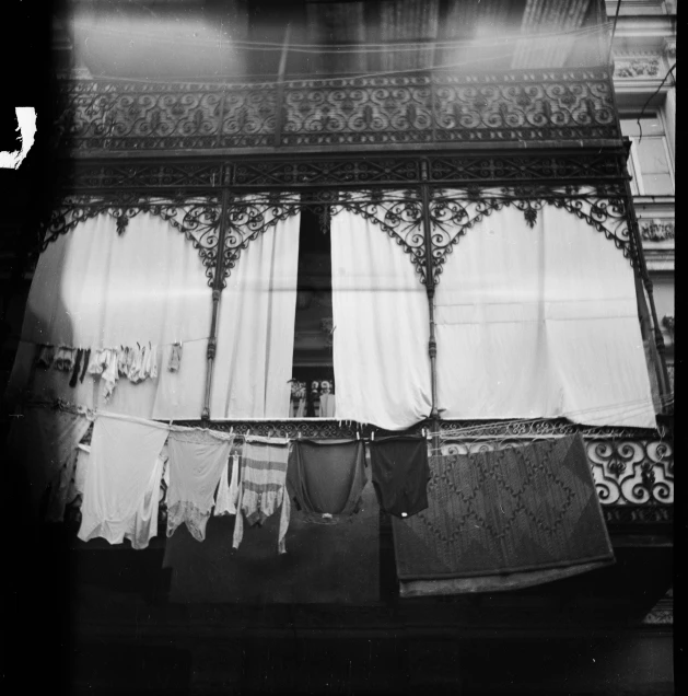 a black and white photo of clothes hanging out to dry, by Maurycy Gottlieb, art nouveau, with screens and silks, tiles curtains, ( ( photograph ) ), paisley