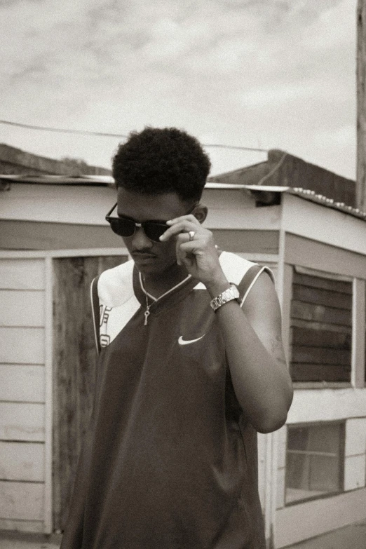 a black and white photo of a man talking on a cell phone, an album cover, by Afewerk Tekle, unsplash, les nabis, teenage boy, with sunglass, low quality grainy, afro hair