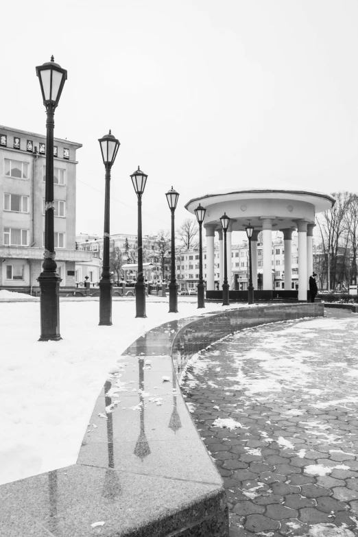 a black and white photo of a park in the snow, a black and white photo, by Vassily Maximov, market square, pillar, round format, white pale concrete city