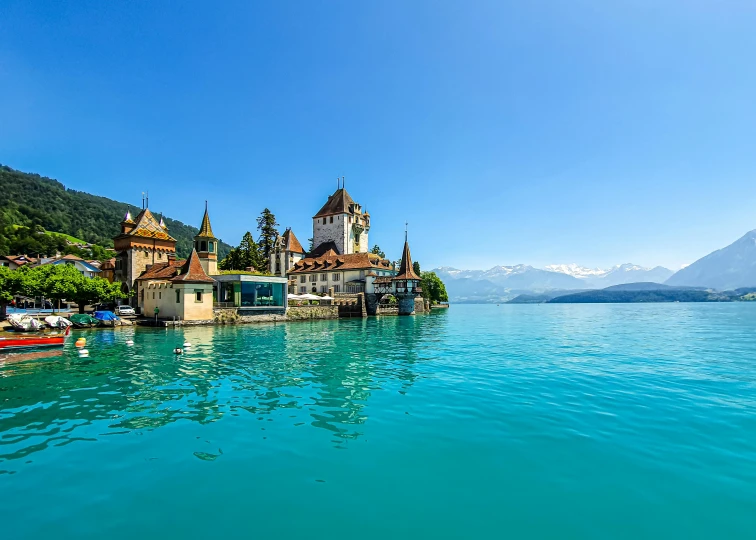 a group of boats floating on top of a body of water, by Julia Pishtar, pexels contest winner, art nouveau, swiss architecture, lake blue, turrets, thumbnail