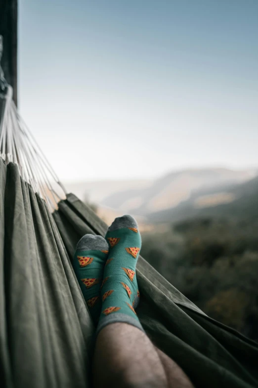 a person laying in a hammock with their feet up, pexels contest winner, teal orange, mountainside, wearing kneesocks, paisley