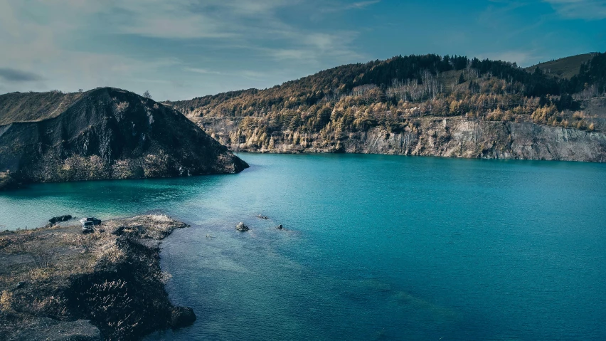 a large body of water surrounded by mountains, by Jesper Knudsen, pexels contest winner, black cyan gold and aqua colors, rock quarry location, thumbnail, northern france