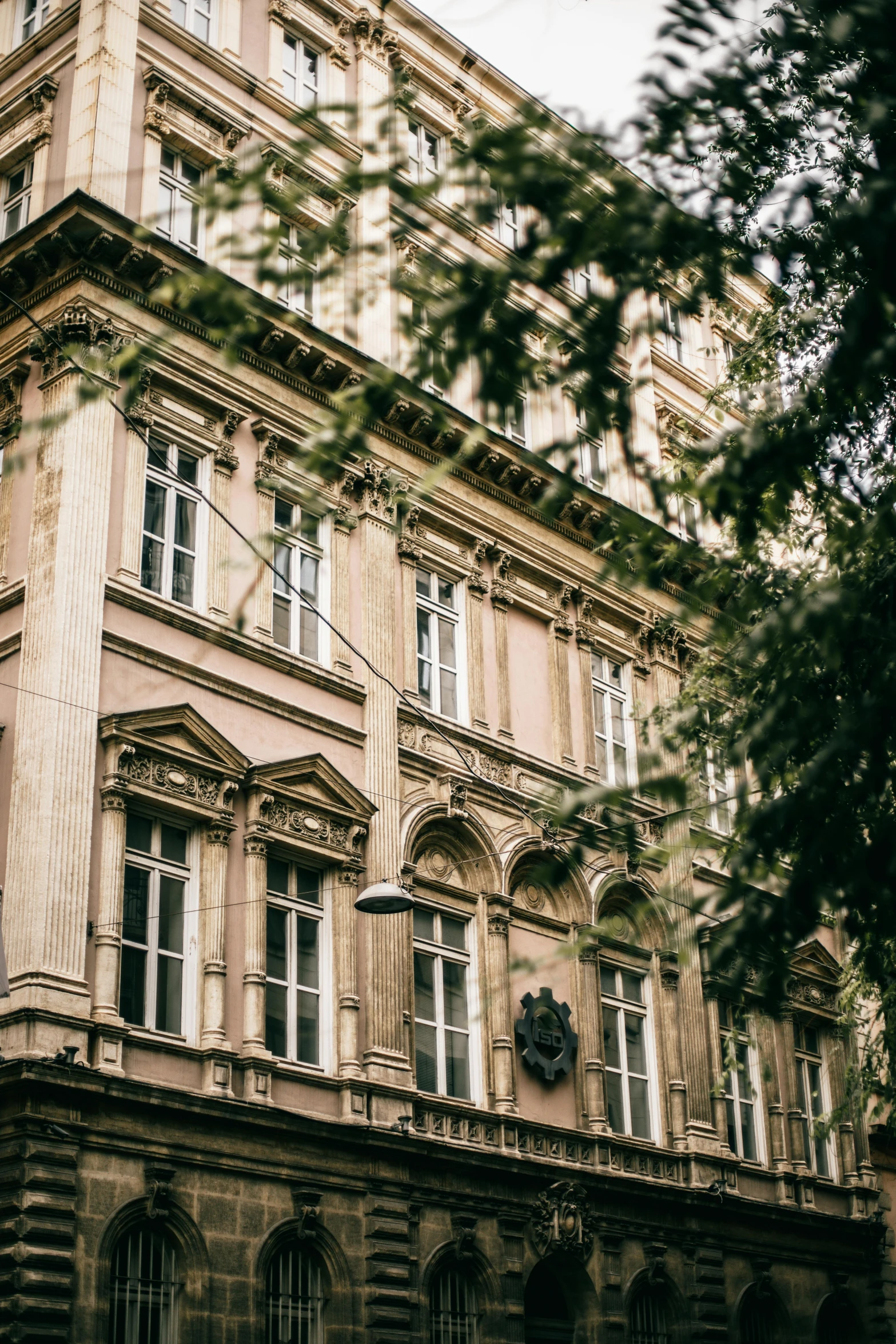 a tall building with a clock on the front of it, a photo, unsplash contest winner, danube school, massive trees with warm windows, splendid haussmann architecture, austro - hungarian, old apartment