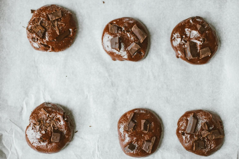 chocolate cookies are lined up on a baking sheet, a portrait, unsplash, background image, 6 pack, pointè pose, melted