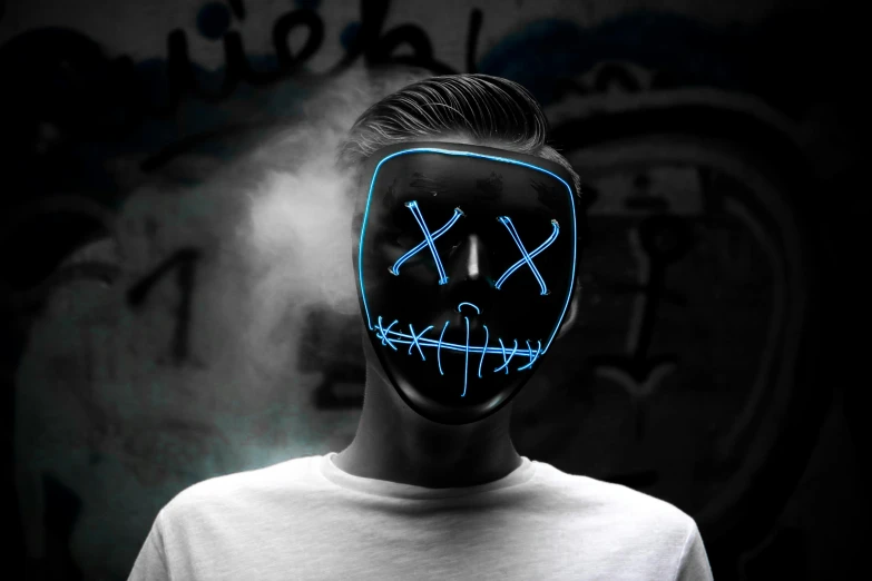 a man wearing a neon mask in front of a graffiti wall, an album cover, trending on pexels, illuminated blue neon lines, hyperrealistic image of x, halloween, black mask