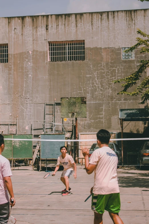 a group of young men playing a game of tennis, inspired by Zhang Kechun, pexels contest winner, wearing a volleyball jersey, back alley, phong shaded, full building