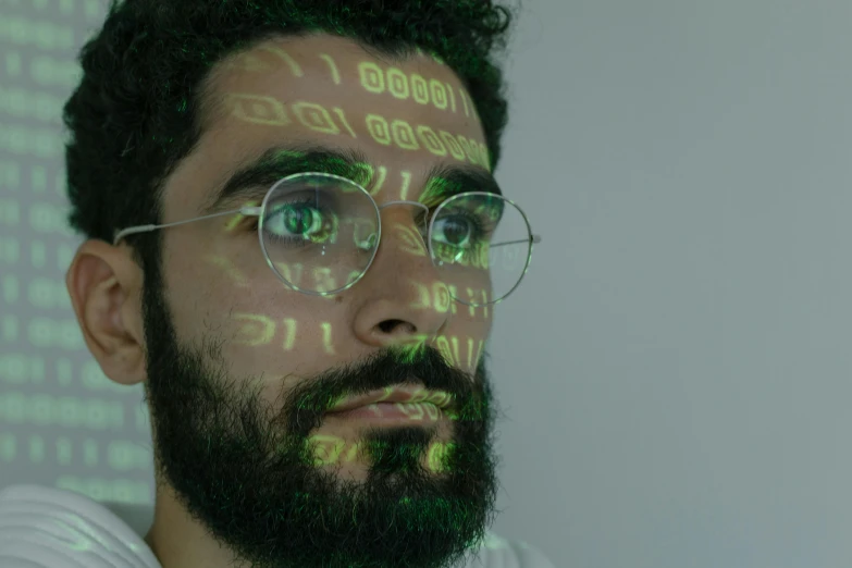 a close up of a man with glasses and a beard, a hologram, pexels, arab man light beard, hacking into the mainframe, who is a male android, eyes are green lights
