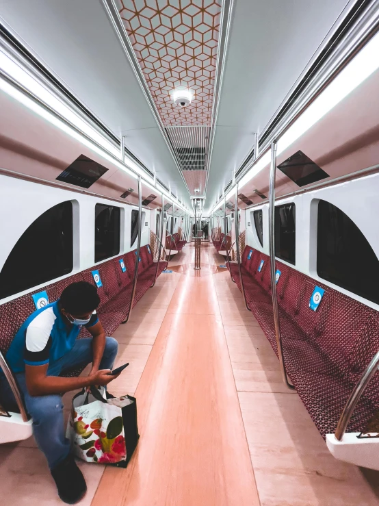 a man sitting on a train looking at his cell phone, an album cover, pexels contest winner, hyperrealism, infinitely long corridors, train with maroon, lined with neon tube lights, taken in 2022