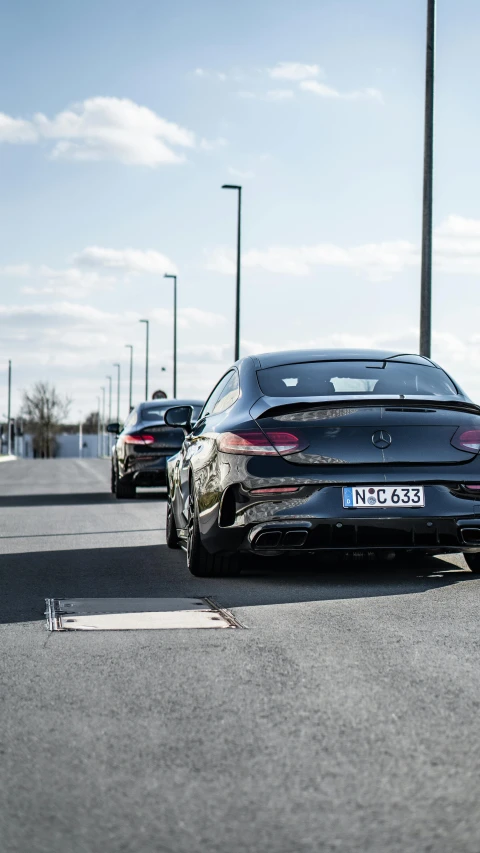 a couple of cars that are sitting in the street, facing away from the camera, mercedes, on a racetrack, low quality photo