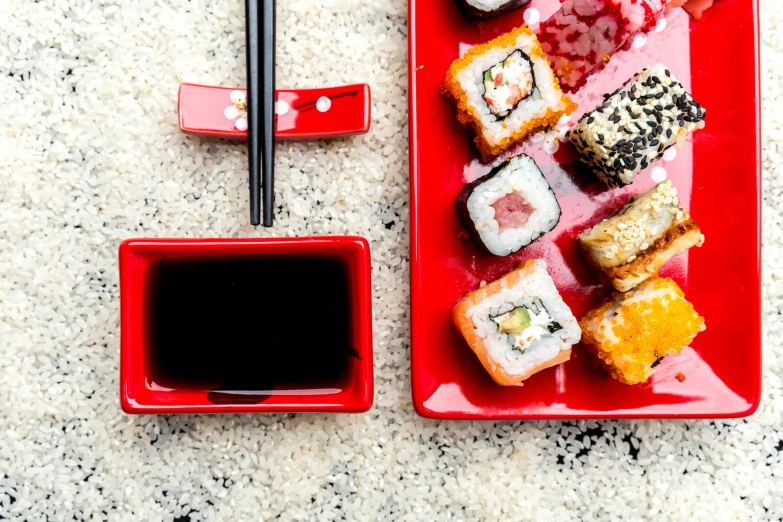 a red plate topped with sushi and chopsticks, by Julia Pishtar, square, black, commercial photo, thumbnail