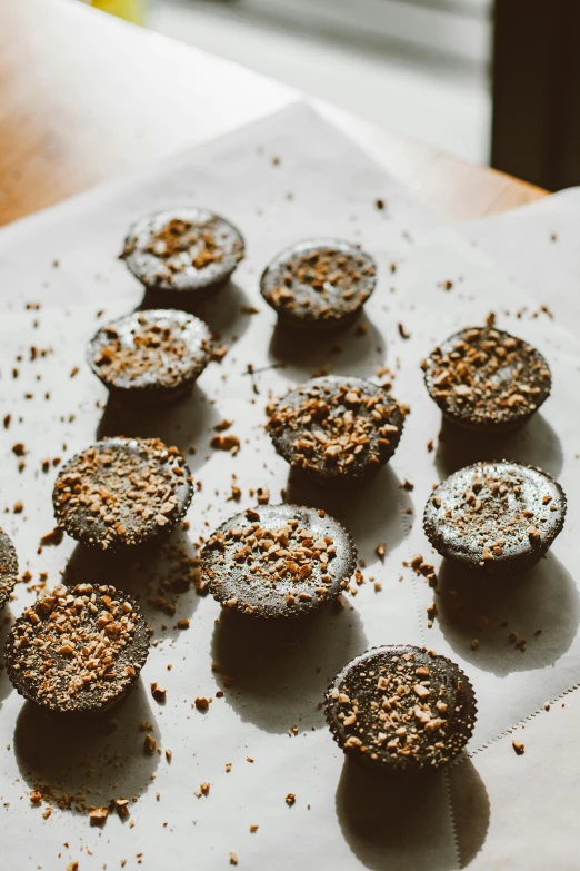 a white plate topped with chocolate cupcakes on top of a wooden table, by Jessie Algie, unsplash, shell craters, dust, very crispy, many holes