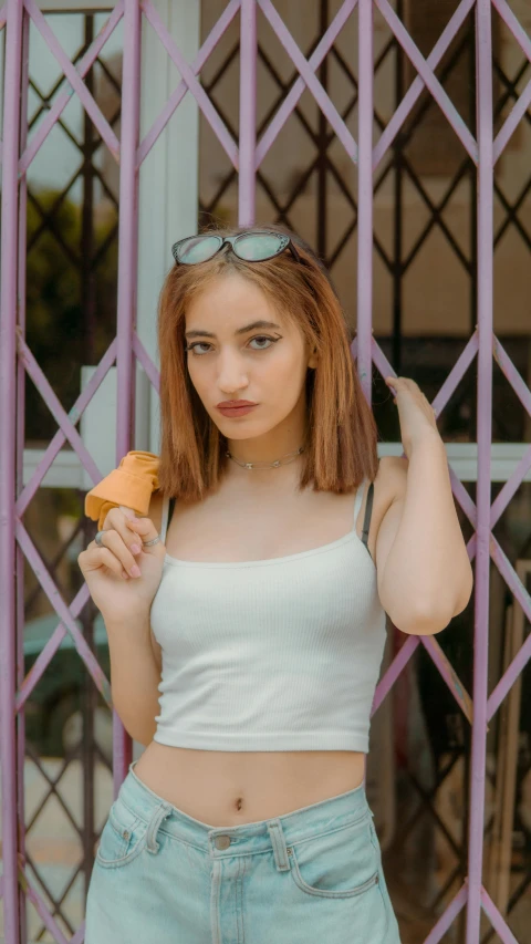a woman standing in front of a gate holding a donut, inspired by Elsa Bleda, pexels contest winner, realism, ice cream cone, wearing a camisole, attractive young woman, white and orange