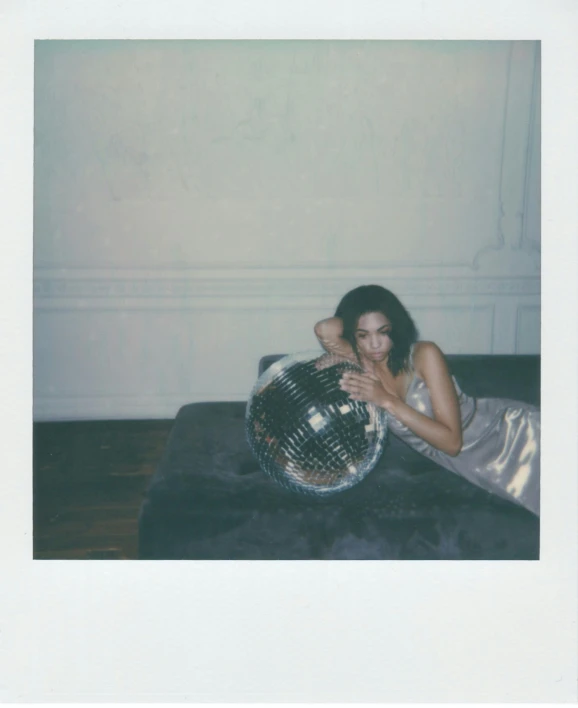 a woman laying on a couch with a disco ball, a polaroid photo, bella hadid, slightly minimal, violet myers, ( ( photograph ) )