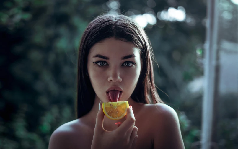 a woman holding an orange slice in front of her face, inspired by Elsa Bleda, pexels contest winner, sexy lips, 🍸🍋, ukrainian girl, long tongue