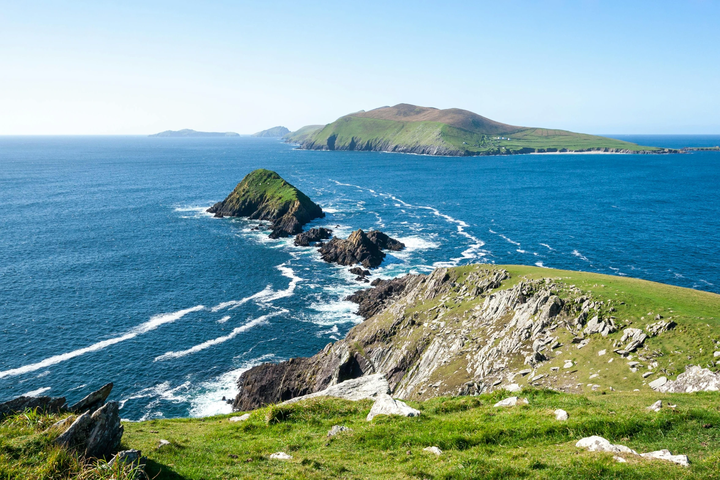 a large body of water sitting on top of a lush green hillside, a photo, inspired by Mór Than, pexels contest winner, many islands, coastal cliffs, thumbnail, eeriewave