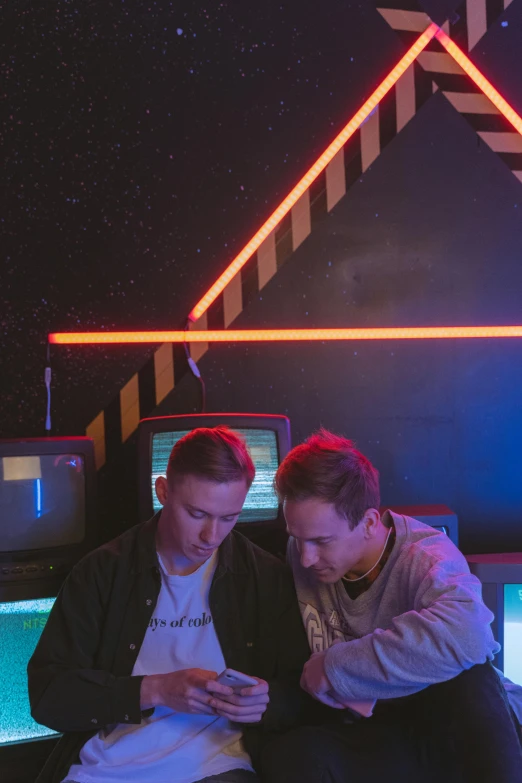 two men sitting on a bench looking at a cell phone, inspired by Beeple, pexels, computer art, standing in a starbase bar, lasers and neon circuits, in front of a computer, space craft