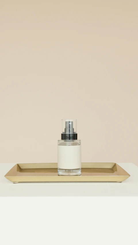 a bottle of lotion sitting on top of a tray, minimalism, gold mist, thumbnail, jakarta, no - text no - logo