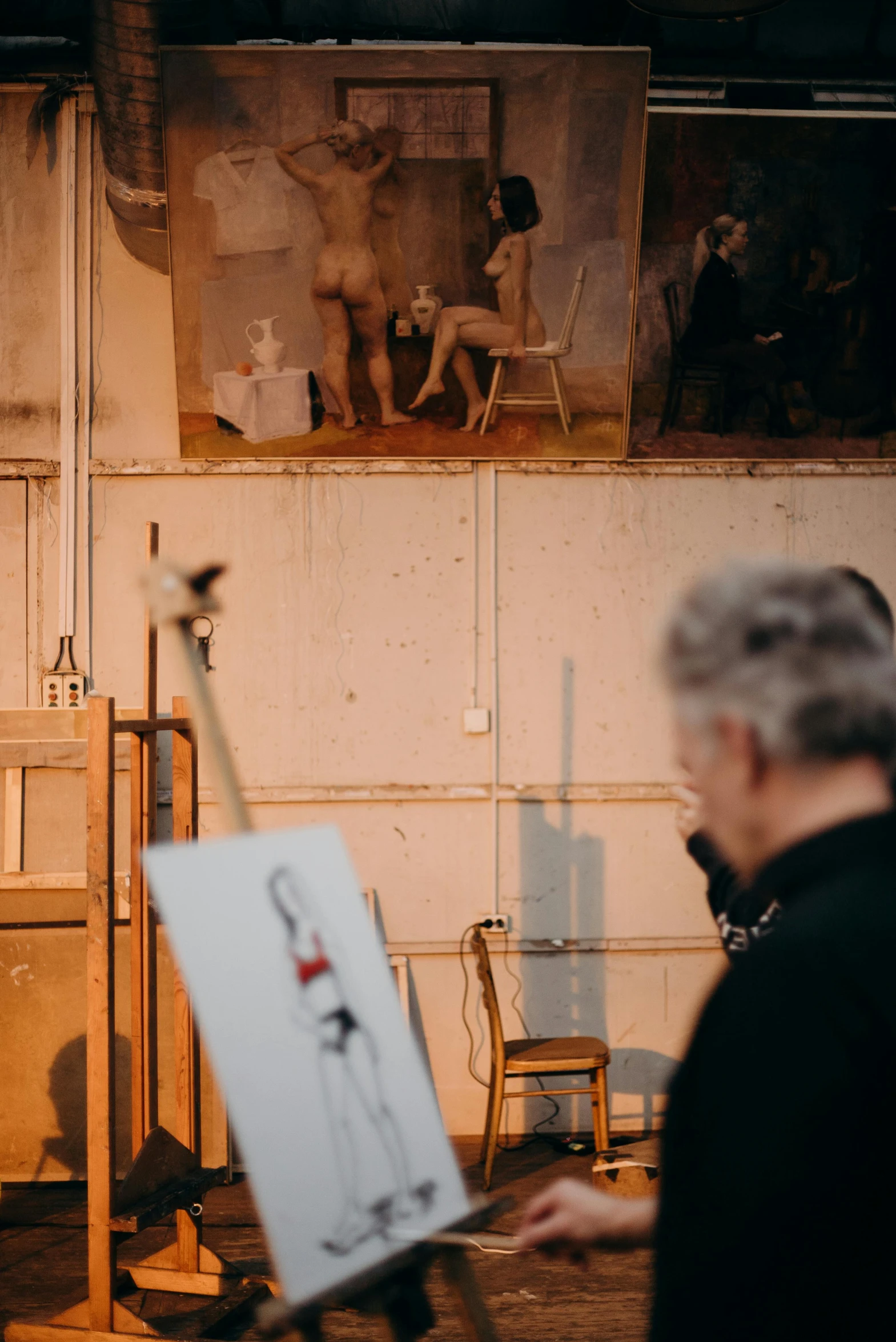 a man that is standing in front of a painting, inspired by Sir William Orpen, trending on unsplash, stands at her easel, photographed from behind, concert, in a workshop