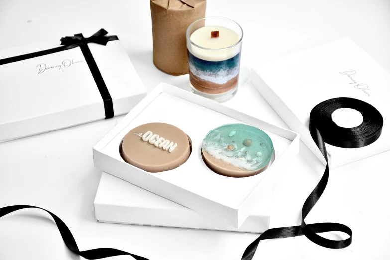 a couple of cookies sitting on top of a box, inspired by Eden Box, realistic ocean, award winning modern design, cosy, art set