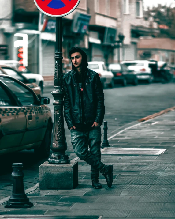 a man walking down a street next to a traffic sign, an album cover, inspired by Elsa Bleda, trending on pexels, wearing a full leather outfit, portrait mode photo, crossed arms, sayem reza