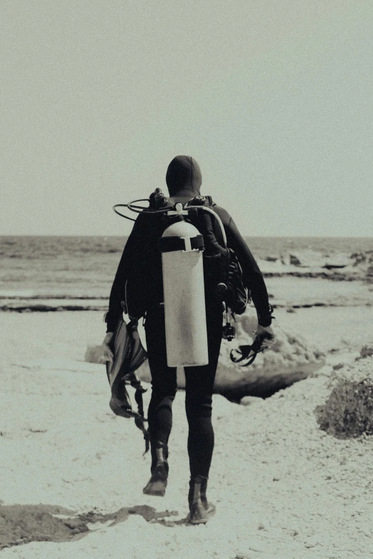 a black and white photo of a man carrying a surfboard, a black and white photo, unsplash, diving suit, reefs, sepia, a man wearing a backpack