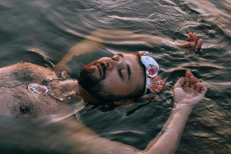 a man with goggles floating in a body of water, inspired by Elsa Bleda, pexels contest winner, renaissance, he is covered with barnacles, flower child, sleeping, attractive man